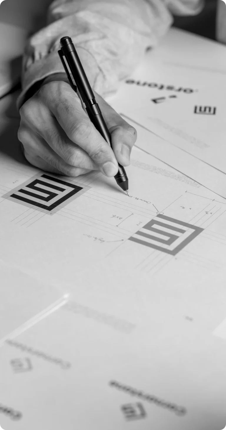 Person designing logo on paper with pen.